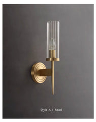 Gold wall sconce with clear glass shade on a dark gray background