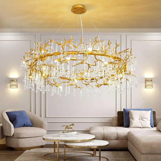 Gold branch-style chandelier with cascading clear crystals hanging over a modern living room furniture arrangement.