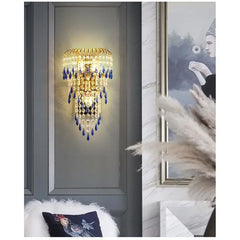 Decorative wall light fixture with blue accents on a gray wall, with a blurred background.