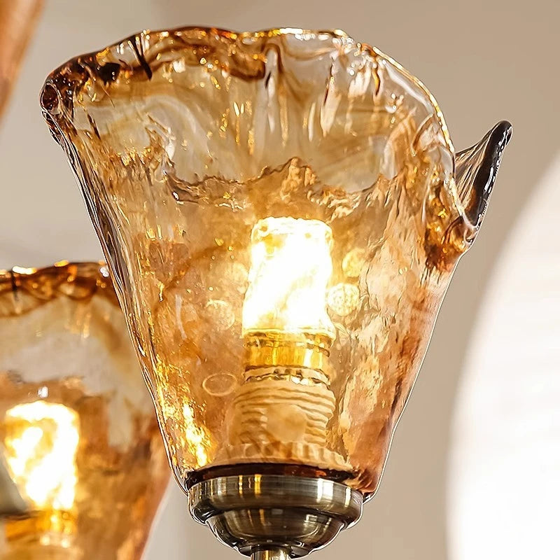 Detailed view of an amber art glass shade on the chandelier, showing the texture and glow of the internal LED bulb.