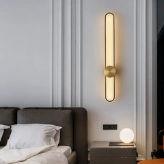 Modern wall lamp on a white wall above a bed in a bedroom setting.