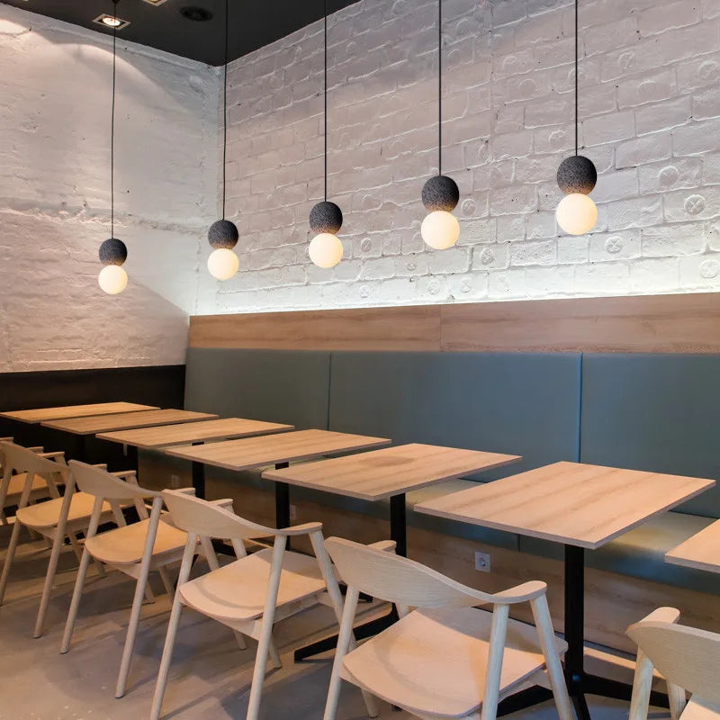 Modern restaurant interior with tables and chairs under pendant lights.