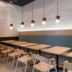 Modern restaurant interior with tables and chairs under pendant lights.