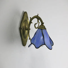 Wall-mounted lamp with blue glass shade and brass fixture on a white background
