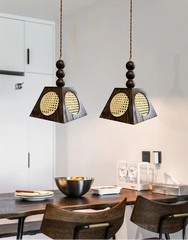 Two wooden pendant lights hanging above a dining table with chairs.