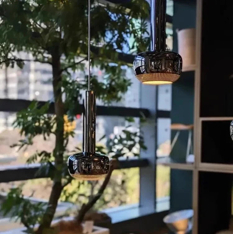 Modern pendant lights hanging above a sofa with decorative pillows in a living room setting.
