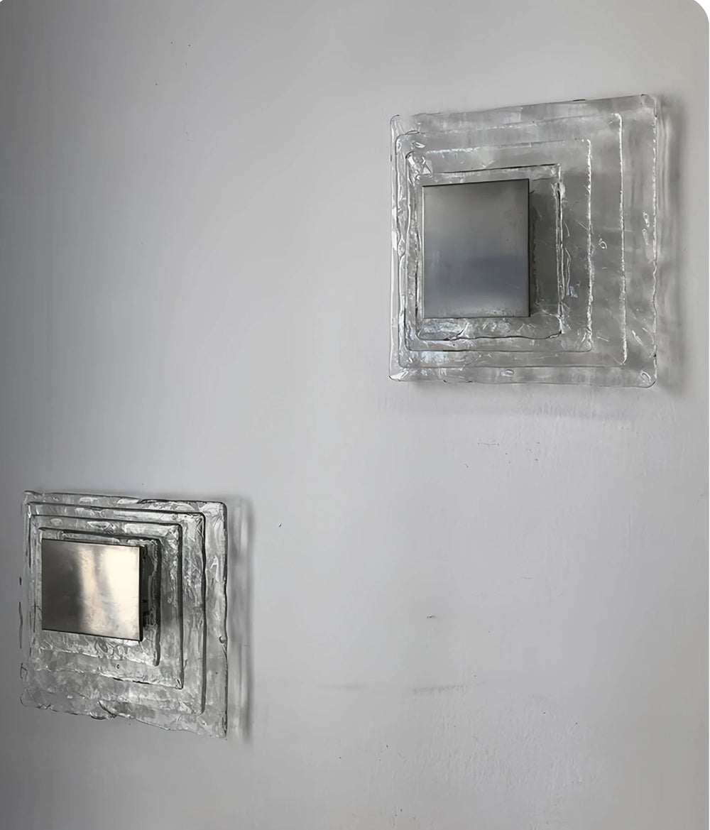 Two square metallic wall art pieces on a gray background