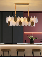 Modern chandelier hanging above a kitchen counter with a dark cabinet and pink wall in the background.