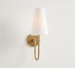 Wall-mounted light fixture with white shade and gold fixture on a plain background