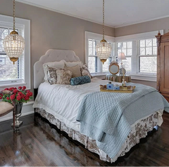 Neatly made bed with decorative pillows and a tray in a well-lit bedroom.
