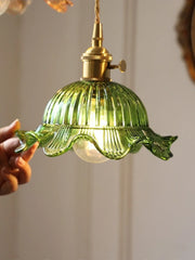Green glass pendant light with gold fixture against a neutral background