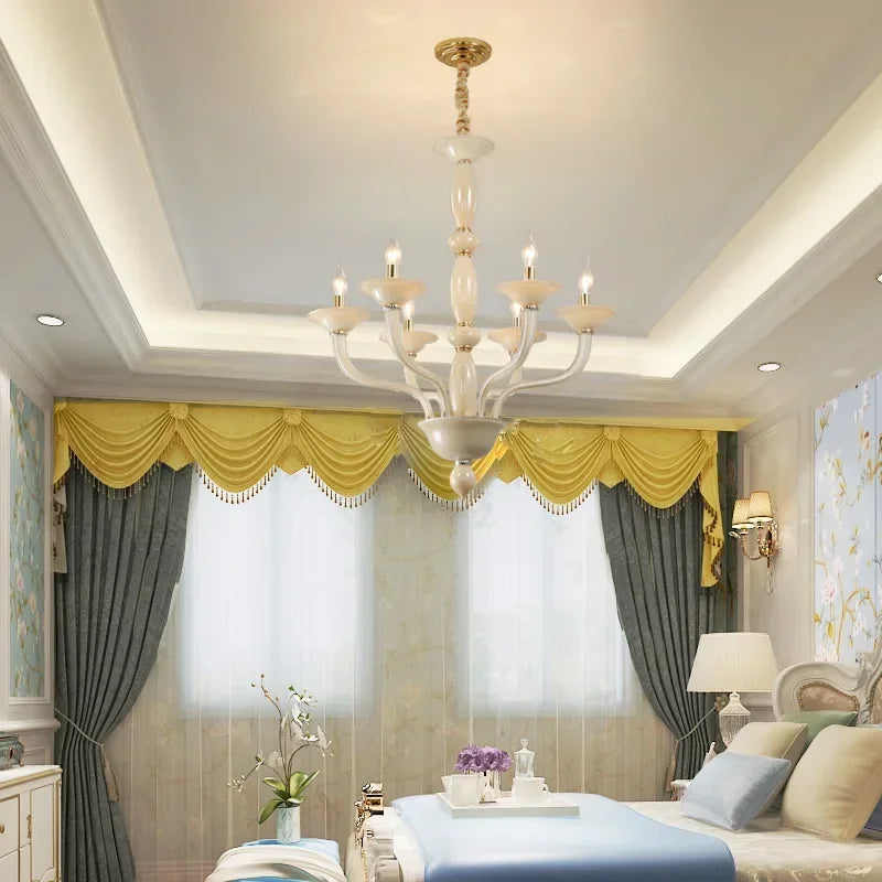 A champagne ceramic and glass chandelier installed in a bedroom with yellow drapes and grey curtains.