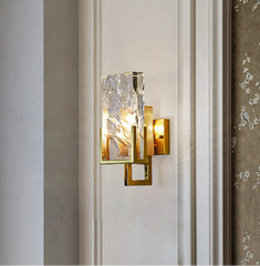 Decorative wall sconce with glass shade on a neutral wall.