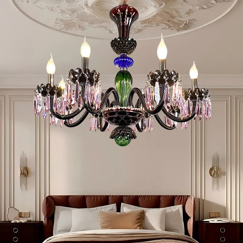 Close-up of a multi-colored crystal chandelier with candelabra-style arms, illuminating a bedroom.
