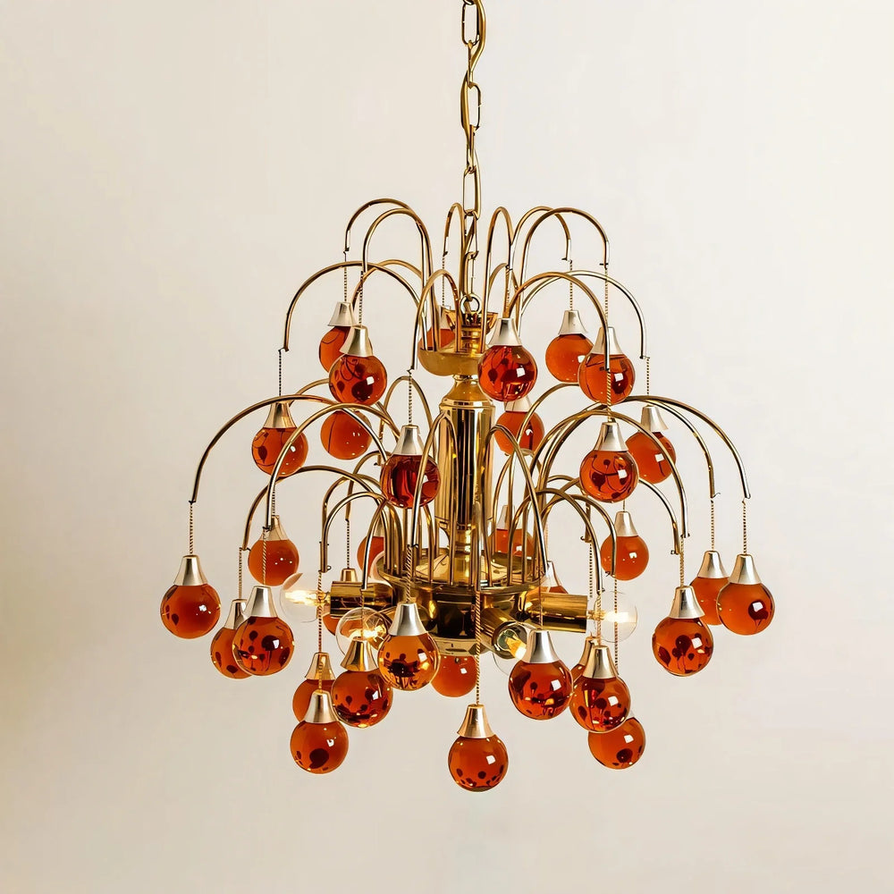 Gold chandelier with cascading amber teardrop glass pendants against a white background
