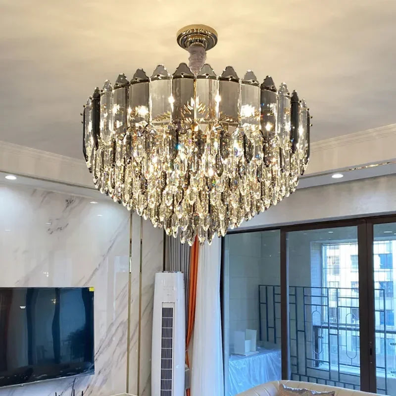 A wide shot of a living room featuring a large, ornate chandelier with a gold frame and crystal accents, illuminating the space.