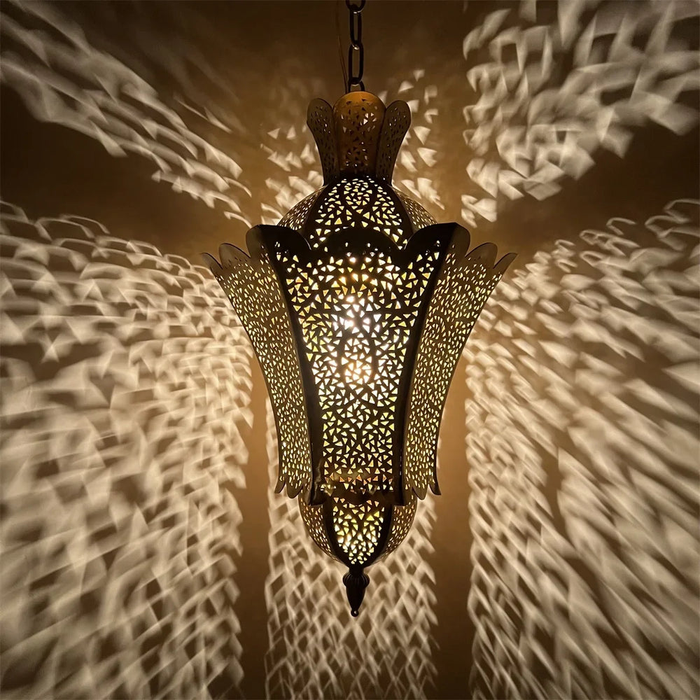 A close-up view of a gold hollow carved floral pendant light with internal light source.