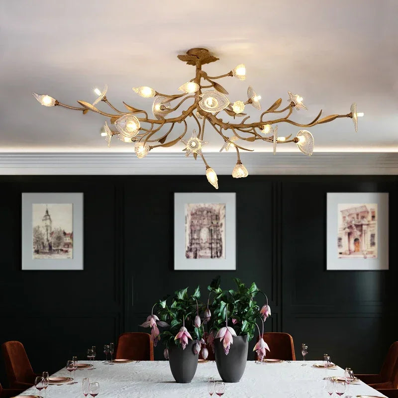 Gold chandelier hanging above a dining table with dark walls and framed pictures.