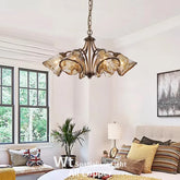 Bedroom with a copper floral chandelier featuring smoked glass shades hanging above a bed.