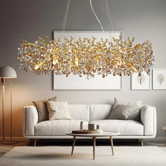 Gold crystal chandelier with a branch-like design and clear faceted crystals hanging above a white sofa in a living room setting.