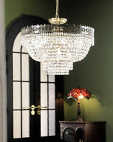 Tiered crystal waterfall chandelier with polished chrome frame hanging in a room with a dark arched doorway and green walls.