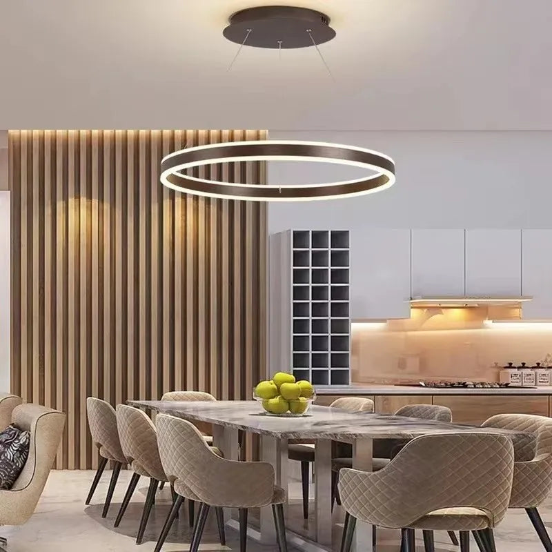 A dining room setting featuring a dark frame ring pendant light above a stone-top table.