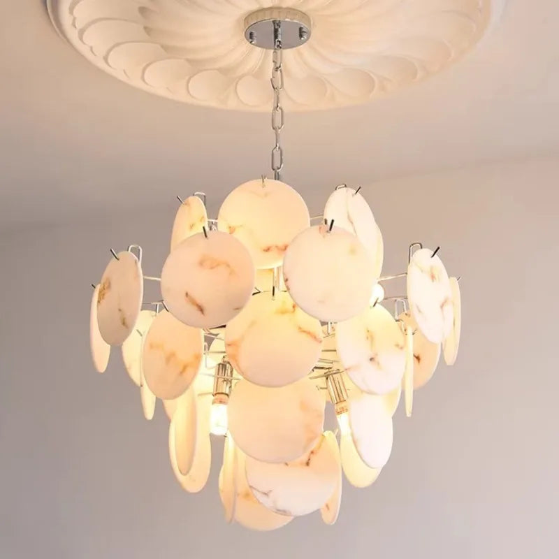 Close-up of the illuminated faux alabaster marble discs on a polished chrome chandelier, highlighting the marble-like veining.