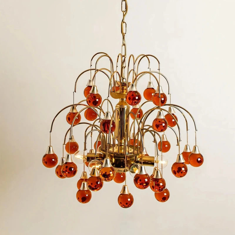 A similar chandelier design in a red/amber hue with gold metal accents.