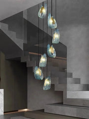 Modern chandelier with glass shades hanging above a staircase.