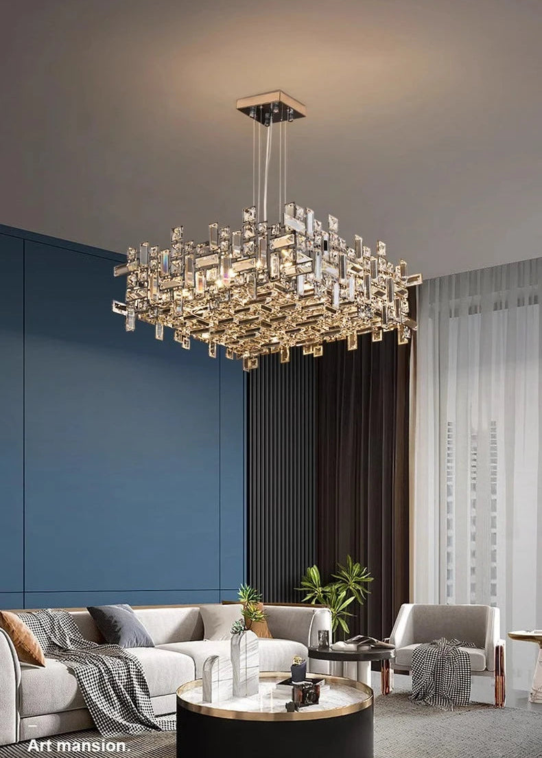 Modern chandelier hanging in a stylish living room with blue walls and gray furniture.