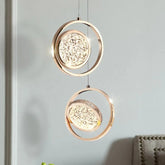 Two gold ring pendant lights with crystal diffusers hanging against a grey wall.