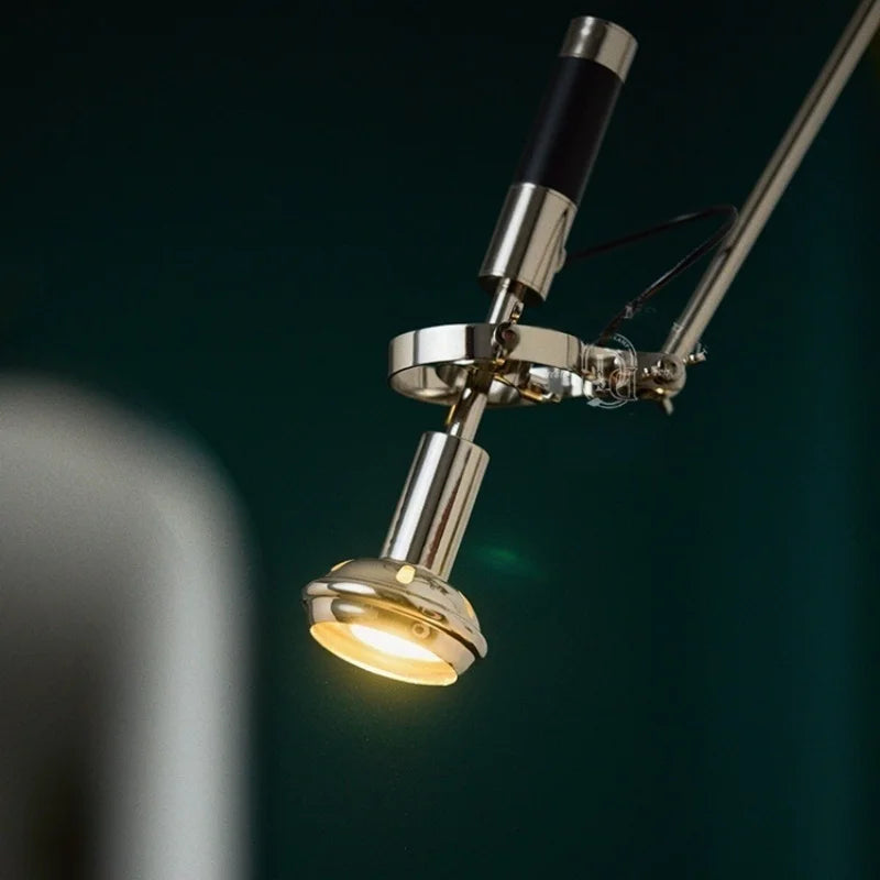 Detail of the illuminated LED light head on a polished chrome and black adjustable swing arm wall sconce.