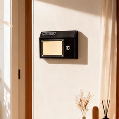Black retro radio shaped wall sconce mounted on a white wall, illuminated by warm light.
