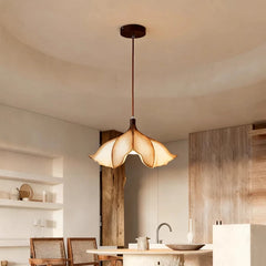 Beige floral pendant light hanging from a dark brown cord and ceiling canopy in a bright, modern kitchen or dining area with wooden accents.