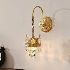 Decorative gold wall sconce with crystal accents on a white wall.