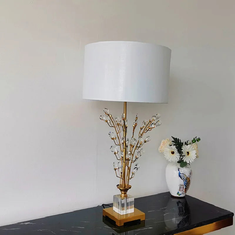 Decorative lamp with crystal branch design on a black surface against a white wall
