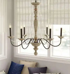 Wooden chandelier hanging in a room with light-colored walls and window blinds.