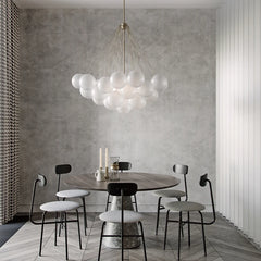 Modern dining room with a round table and chairs under a bubble-like chandelier.
