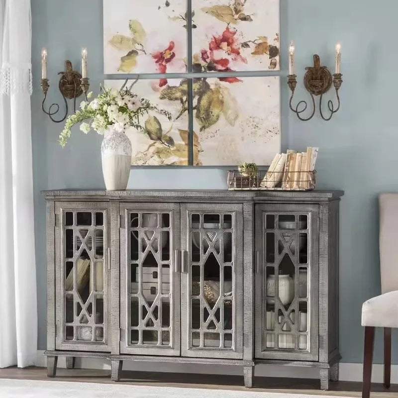 Decorative sideboard with floral painting, candles, and books against a light blue wall.
