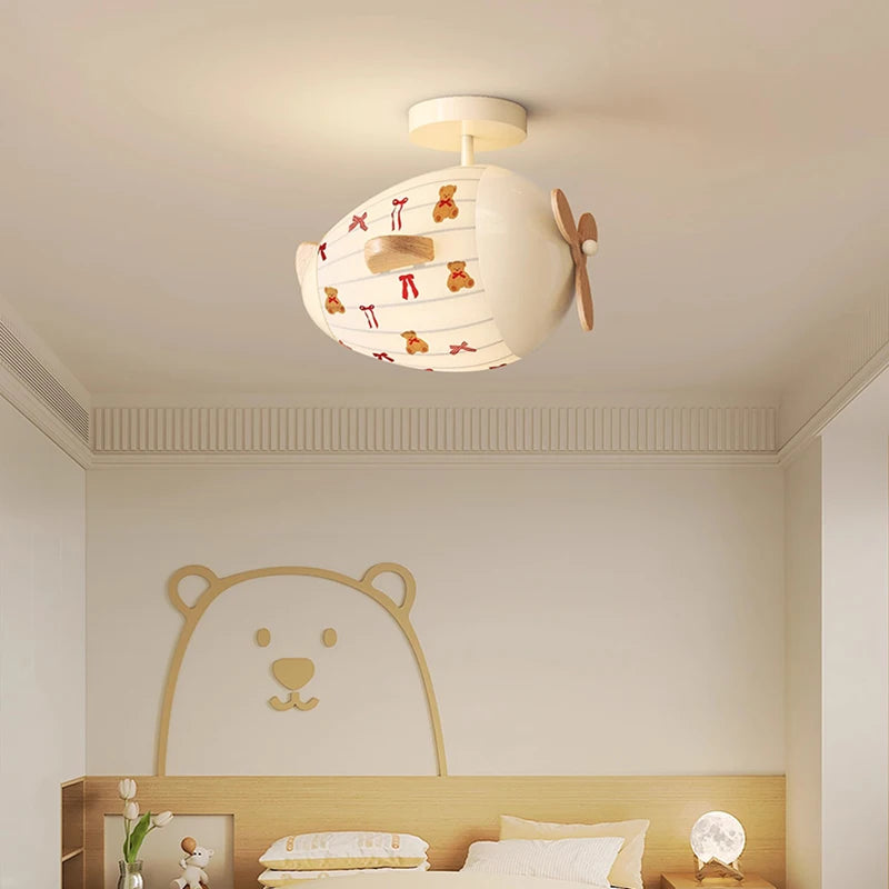 Children's room ceiling light in an airplane design with a fabric shade decorated with teddy bears.