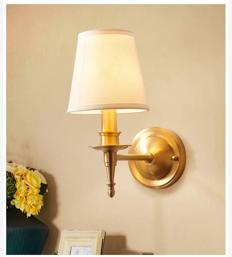 Close-up of a brass wall sconce with a white fabric cone shade and a decorative finial.