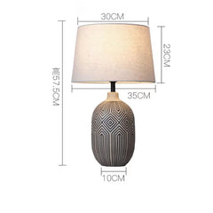 Table lamp with geometric design on base and plain lampshade, shown with dimensions.
