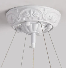 Decorative white ceiling rose with three light fixtures on a plain background