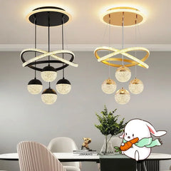 Two modern pendant lights in black and gold hanging above a dining table with decorative elements.