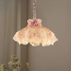 Side view of a fabric pendant light featuring a pink rose and layered, ruffled fabric shades emitting a warm glow.