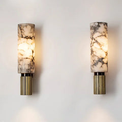 A pair of wall sconces with natural marble shades and reeded brass bases shown on a white wall.