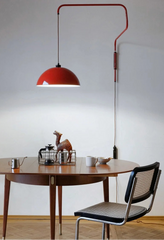 Dining area with a red pendant light, wooden table, and black chair.