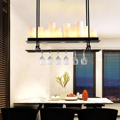 Dining room with a modern pendant light fixture featuring wine glasses and candles.