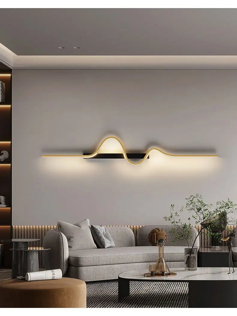 A long, horizontal gold wave wall fixture mounted above a sofa in a living room.