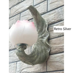 Decorative wall light fixture with pink lampshade on a stone wall background